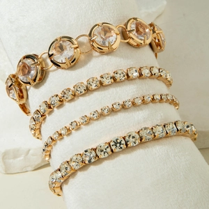 Detailed macro view of four-piece gold plated tennis bracelet set with clear crystals