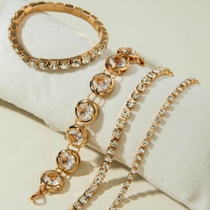 Detail of four-piece gold bracelet set with sparkling crystals on white velvet display