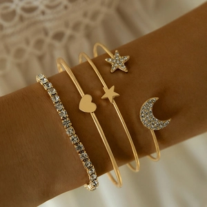 Close-up of golden bangle set featuring sparkling crystal heart and moon charm details