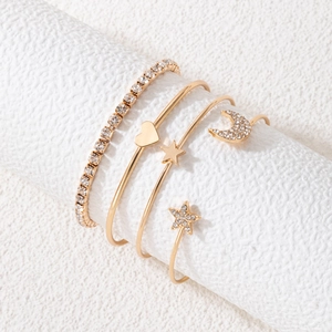 Detail of four-piece gold bracelet set with heart, star, and moon charms on white display