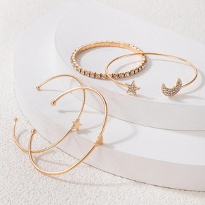 Close-up of gold-plated bracelet set with star and moon charms on white display