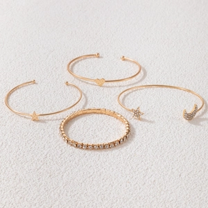 Detail of four-piece gold bracelet set with star and heart charms plus crystal accents