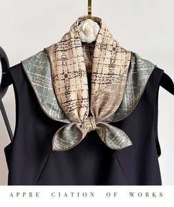 Vue détaillée d'un foulard en soie à carreaux beige et gris bleu noué sur un col noir
