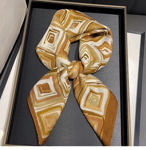 Macro detail of geometric patterned silk square scarf showing silky texture and earth tones