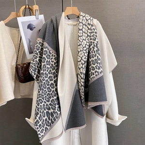 Detail of leopard print patchwork scarf with fine fringe on beige autumn coat
