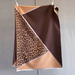 Close-up of geometric leopard print shawl with fringe details and warm knit texture