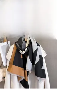Detail of color-block geometric scarf with tassels in black, grey, and caramel cashmere