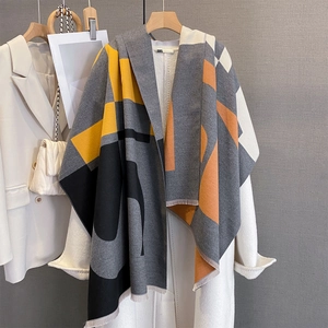 Detail showing geometric color-block scarf with tassels on white wool coat
