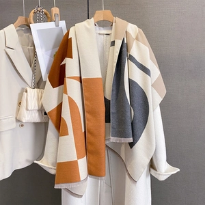 Macro detail of geometric color-block scarf with fine fringe on a white coat