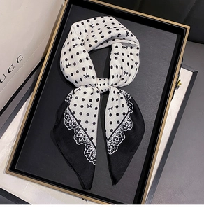 Close-up of black and white polka dot scarf with lace edges and bow pattern on a tray