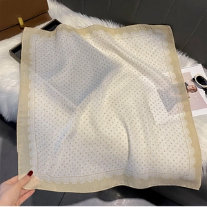 Detail of polka dot silk scarf with lace trim and bow pattern on soft fur mat