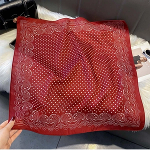 Detailed view of red silk square scarf with white polka dots and paisley patterns