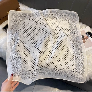 Detailed view of white polka dot scarf with paisley border and elegant accessories