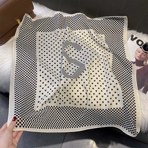 Detailed view of polka dot square scarf with letter S design on plush background