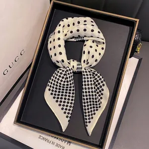 Polka dot silk neck scarf tied in a bow on a tray with elegant accessories