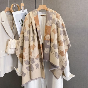 Detail of ginkgo leaf jacquard pattern on a beige scarf hanging on a wooden hanger