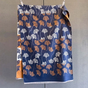 Detail of cashmere-like scarf with blue ginkgo leaf pattern and soft white fringe edge