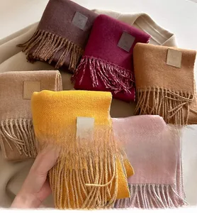 Detailed close-up of wool blend scarf with fringe edges and premium leather label