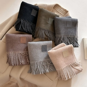 Multi-color wool blend fringe scarves in neutral tones displayed on a beige winter coat
