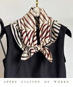Macro detail of geometric twill silk scarf tied elegantly on a black sleeveless outfit