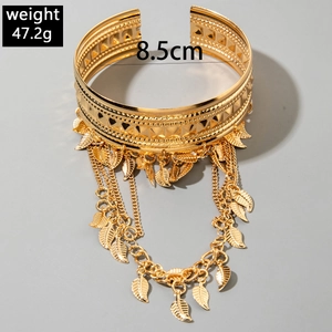 Détail d'un bracelet de bras doré avec motifs embossés et pampilles en forme de feuilles