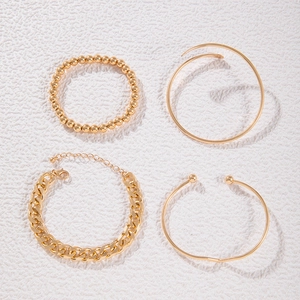 Set of four gold-colored bracelets including a chunky Cuban chain and minimalist bangles