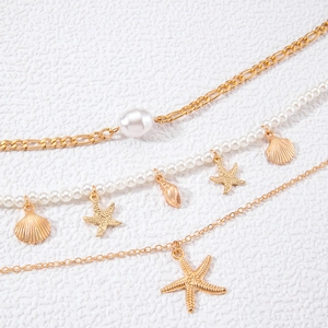 Three-layer ocean theme necklace with starfish pendants and white pearls on sandy texture