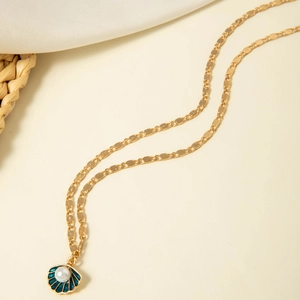 Detailed macro view of a gold shell pendant with blue enamel and a white faux pearl