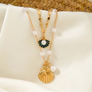 Close-up of layered beaded necklaces with gold sea shells and pearls on silk fabric