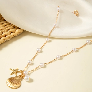 Detail of gold starfish and shell pendants on a layered pearl beach necklace