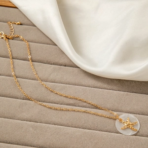 Detail showing a gold starfish pendant on a translucent base with a fine link chain