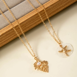 Macro detail of gold sea shell and starfish pendants with pearl on a jewelry tray