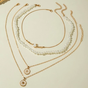 Detail of four-layer gold necklaces with pearls, shell charm, and starburst pendant