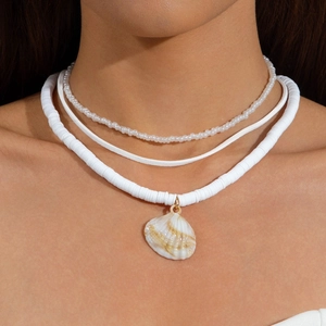 Close-up of triple-layered boho necklace with white heishi beads and natural shell pendant