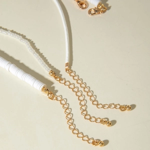 Detail of beaded shell necklaces with gold lobster clasps and white textured beads
