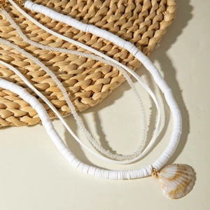 Close-up of bohemian layered beaded necklace with natural seashell pendant on woven mat