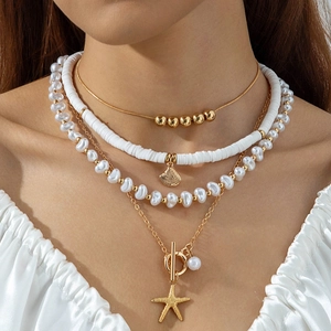 Close-up of multilayered gold necklace with starfish, seashell pendants and pearls