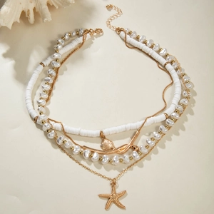 Detail of layered gold starfish and seashell pendants with faux pearls on white beach beads
