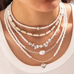 Detail of layered beaded necklace with pearls, stone chips and silver heart pendant