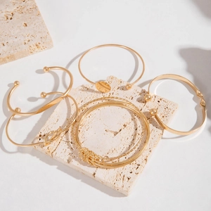 Detailed view of layered gold bangle set with minimalist geometric designs on stone