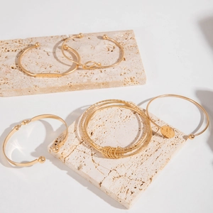 Detail of gold bracelet set with twisted texture and chevron patterns on stone base