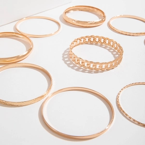 Detailed view of layered gold bangle set with various textures on white background