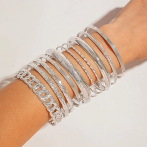 Close-up of stacked silver alloy bracelets featuring cuban chain and engraved patterns