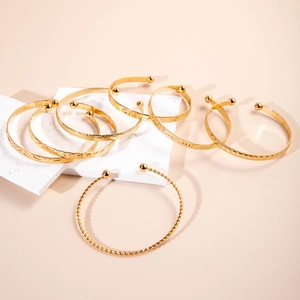 Detailed set of 7 gold-plated bangles with braided, geometric, and polished textures