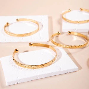 Detailed view of stackable gold textured bangles on a luxury stone display stand