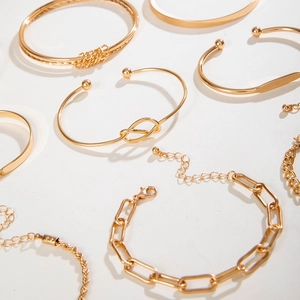 Detailed top view of gold bangle set with arrow patterns and cuban chain links