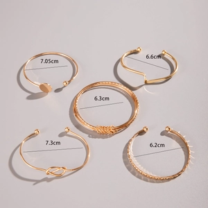 Detail showing five-piece gold bangle set with varied geometric and knot patterns