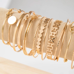 Detail of luxury gold multi-layer bracelets on a velvet display stand with textured patterns