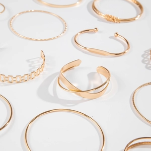 Detailed collection of luxury gold-plated open bangles featuring woven and arrow patterns