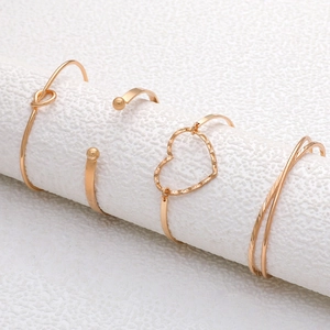 Detail view of 4-piece gold bangle set with knot, heart, and textured geometric designs